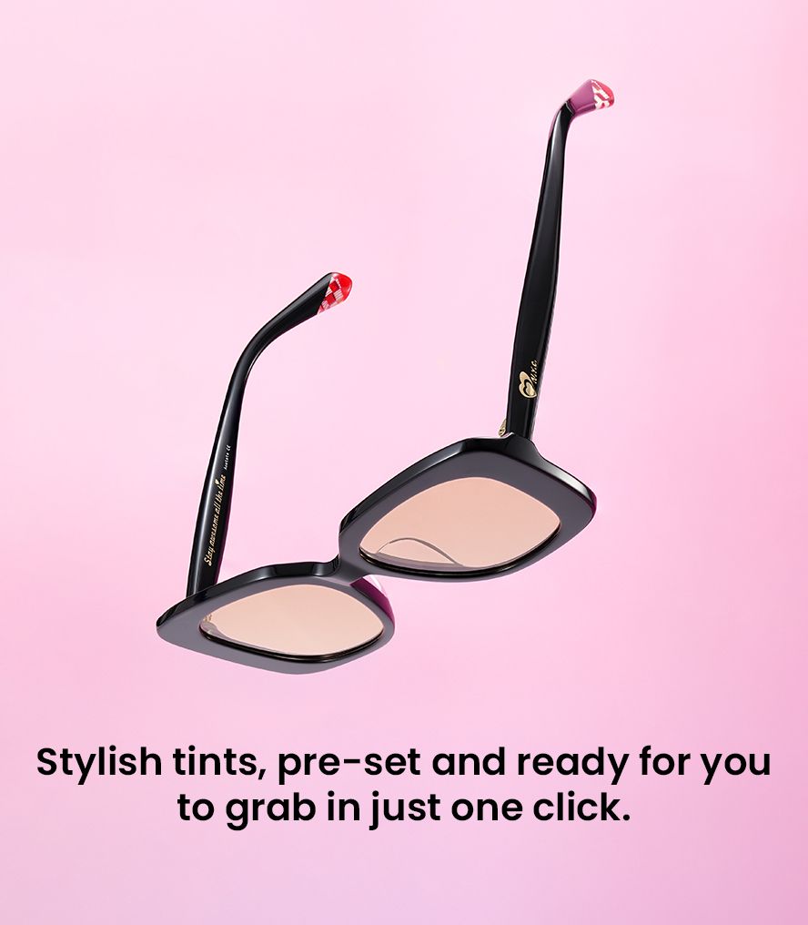 Black cat-eye sunglasses with soft pink tinted lenses against a pastel pink background.