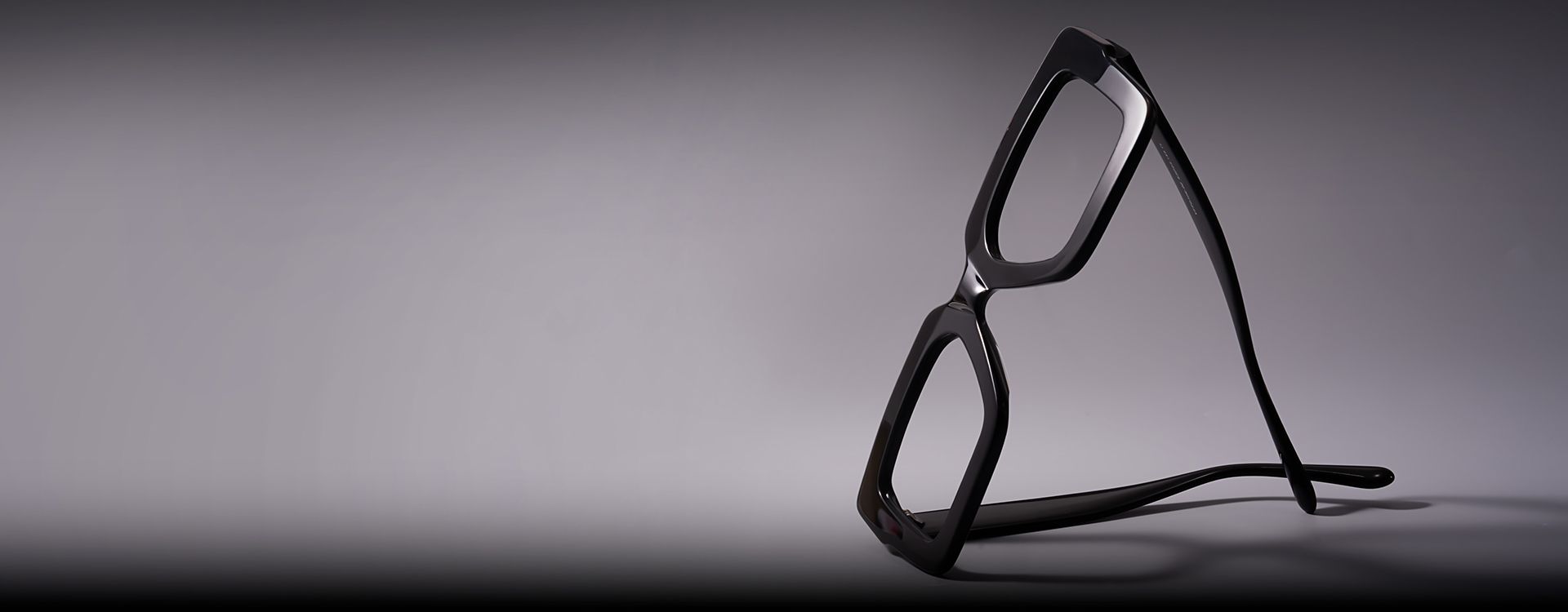 Afro-punk style portrait of a confident individual with braids and bold glasses, set against an orange graphic backdrop.