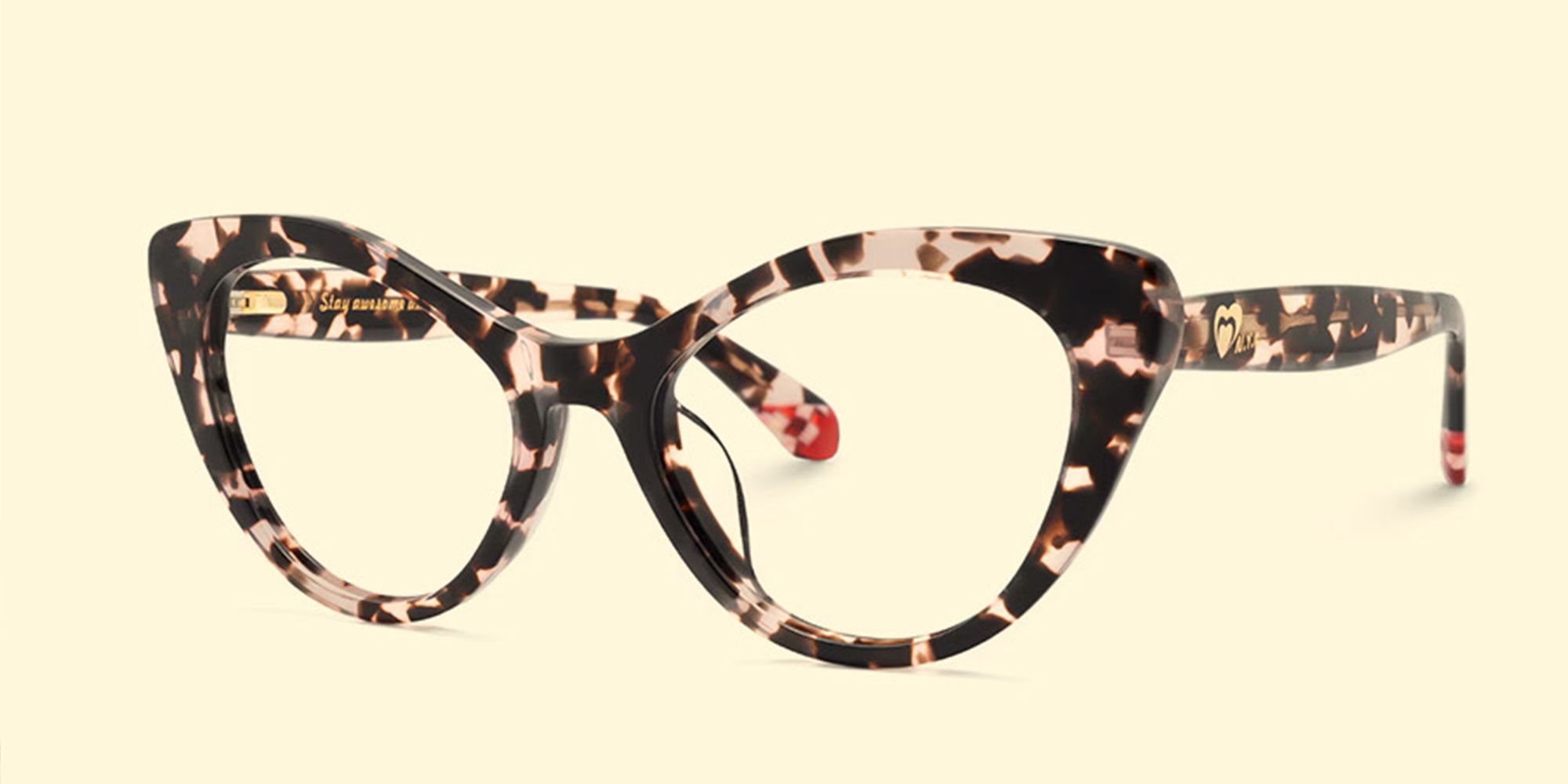 Front view of tortoiseshell cat-eye eyeglasses with a cream and dark brown pattern, displayed against a pale yellow background.