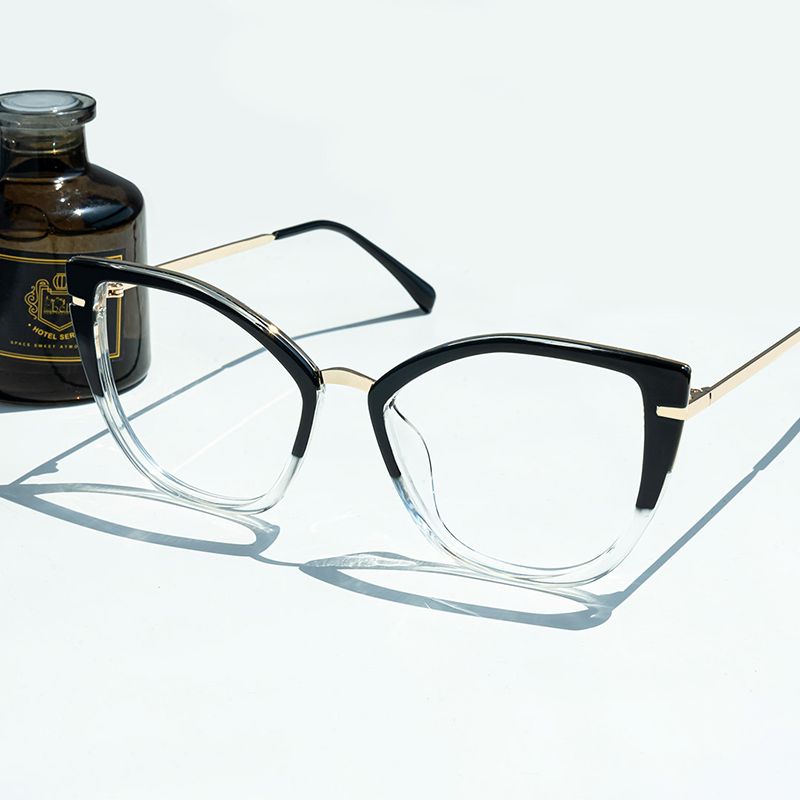 A pair of stylish cat-eye eyeglasses with a black top frame, clear bottom frame, and gold accents against a white background.