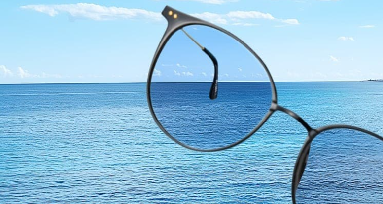 A first-person view of the ocean through a cat-eye sunglass lens, demonstrating how polarized technology removes surface glare to reveal the deep blue color of the water.
