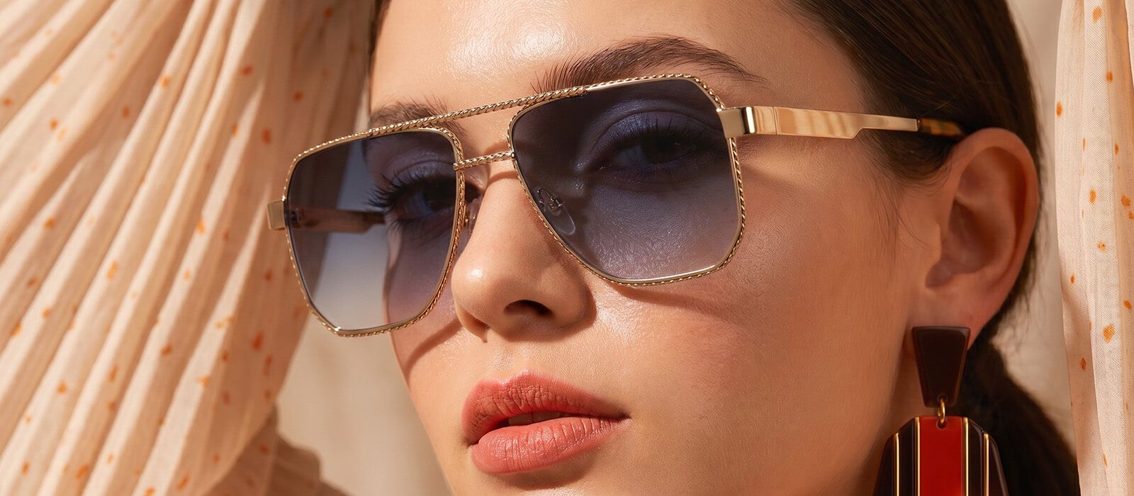 A portrait of a woman looking sideways, accessorized with oversized wire-frame sunglasses featuring a double bridge.