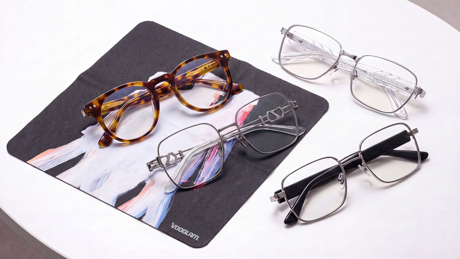 Three pairs of glasses and a lens cleaning cloth