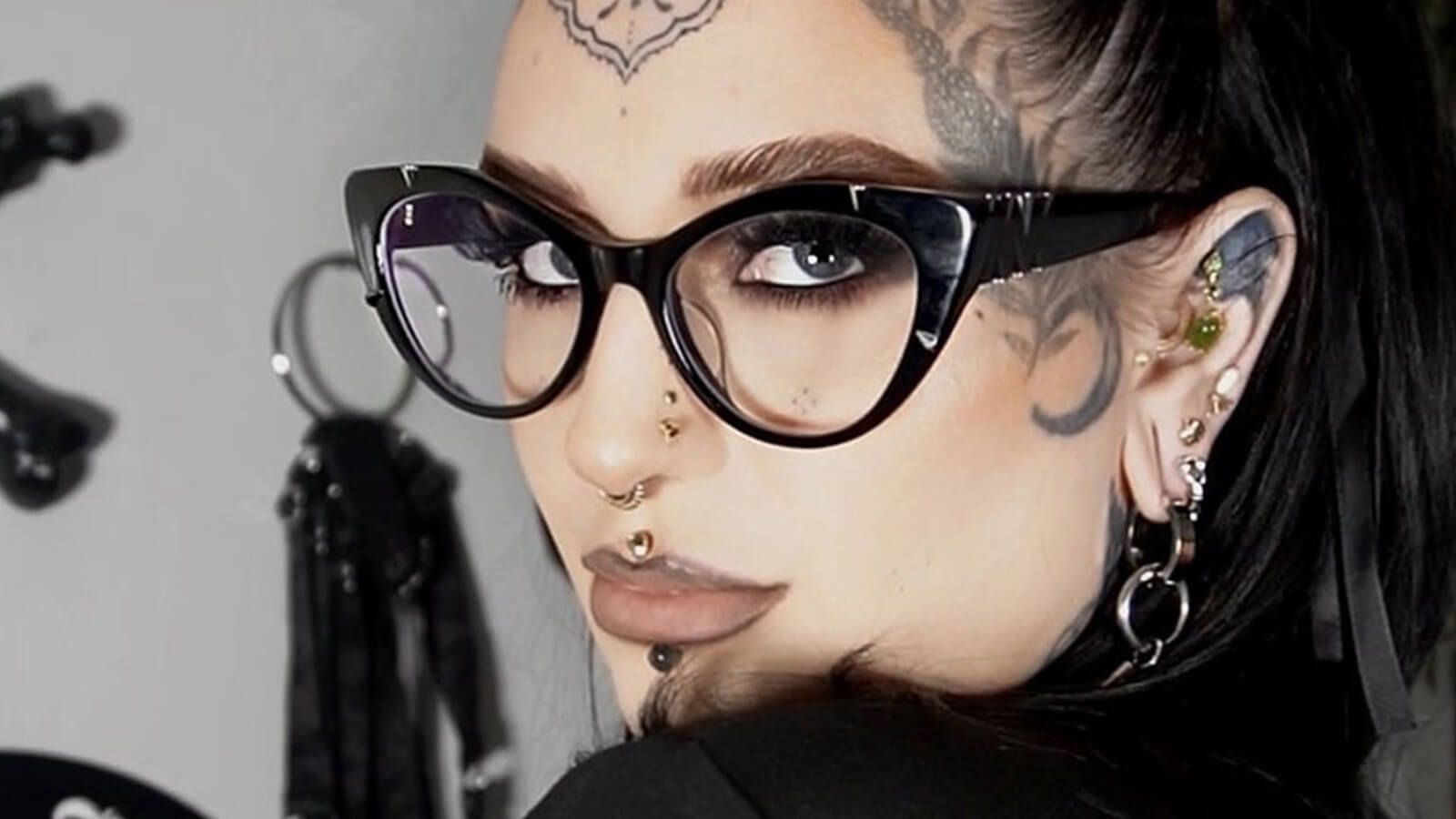 A close-up of a person wearing black cat-eye glasses.