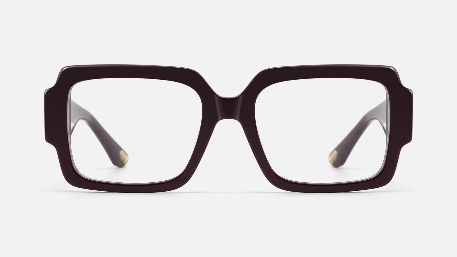 A front view of a pair of thick, dark brown square eyeglasses centered against a solid light gray background.
